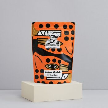 A 1 kilo bag of Colombia Aztec Gold sits atop an ivory coloured platform.
