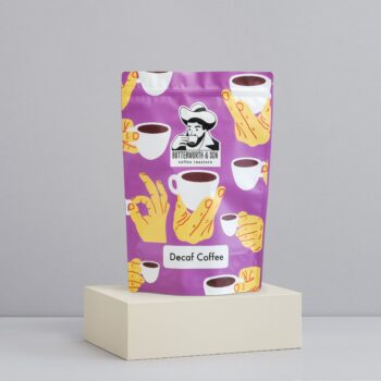 A 1 kilo bag of Decaf Coffee Blend sits atop an ivory coloured platform.
