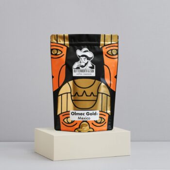 A 1 kilo bag of Mexico Olmec Gold sits atop an ivory coloured platform.